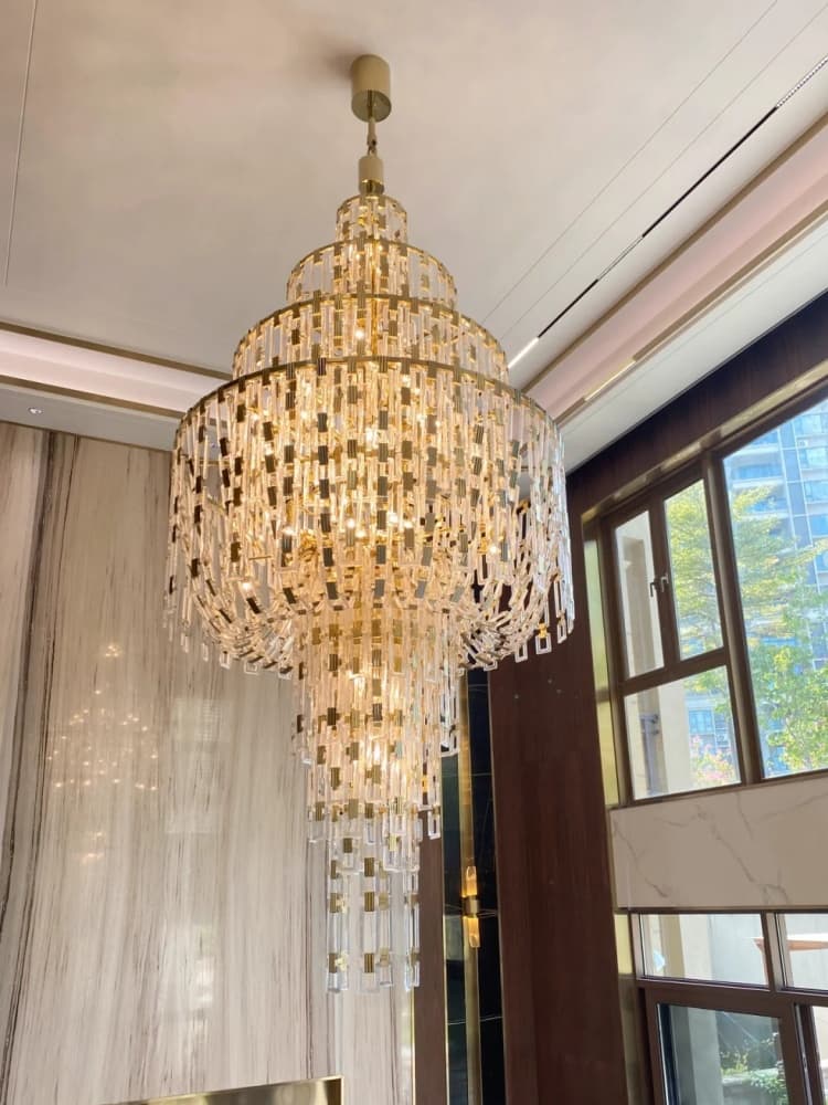 Tiered chandelier with clear rectangular elements beside tall windows